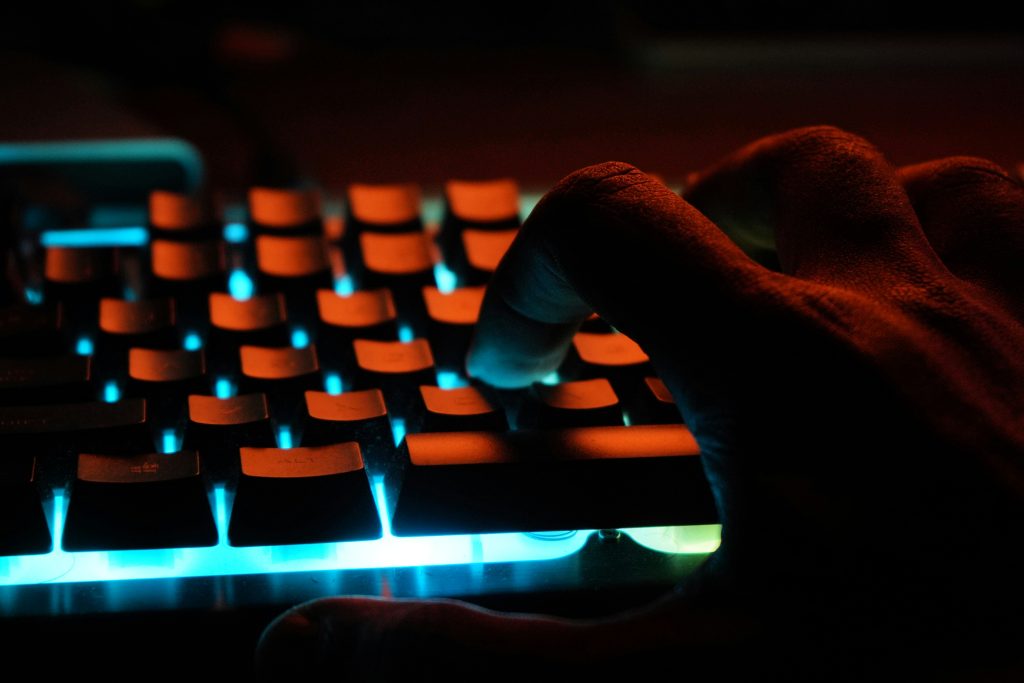 Human fingers on keyboard lit up in red light to illustrate blog post on not using AI writing.