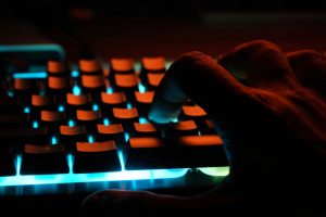 Human fingers on keyboard lit up in red light to illustrate blog post on not using AI writing.
